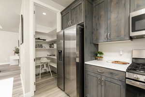 Kitchen with stainless steel appliances, light wood-style flooring, and dark brown cabinets
