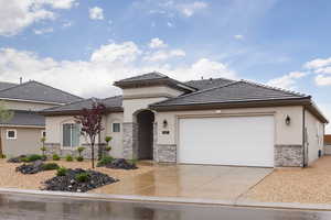 View of front of home featuring stone siding, stucco siding, driveway, an attached garage, and a tiled roof