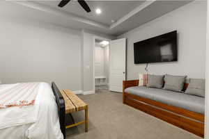 Primary bedroom with light carpet, ceiling fan, a raised ceiling, and recessed lighting