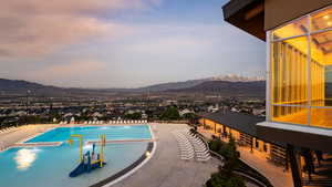 Pool at dusk with a community pool, a mountain view, and a patio