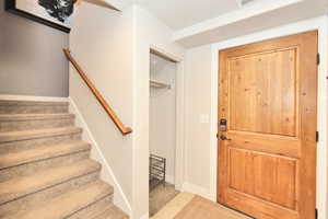 Carpeted foyer featuring baseboards and stairway