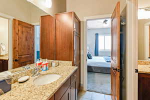 Ensuite bathroom featuring two vanities, light colored carpet, a ceiling fan, and light tile patterned floors