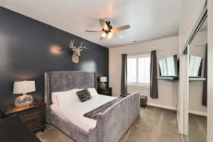 Carpeted bedroom with ceiling fan and baseboards