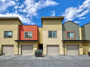 View of front of property with stucco siding, driveway, and a garage