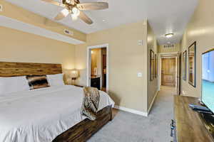 Bedroom with light carpet, connected bathroom, and ceiling fan