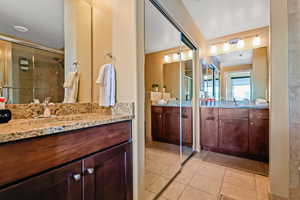 Full bathroom featuring vanity, light tile patterned floors, and a shower stall