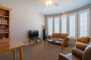 Carpeted living room featuring a ceiling fan, a textured ceiling, and recessed lighting