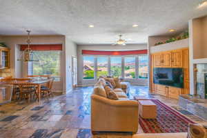 Living area with recessed lighting, plenty of natural light, a textured ceiling, stone tile flooring, and ceiling fan