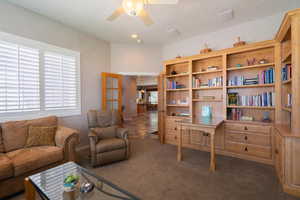 Living area with dark colored carpet, ceiling fan, and a textured ceiling