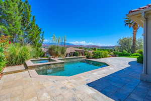 View of swimming pool featuring a patio area, a mountain view, and a pool with connected hot tub