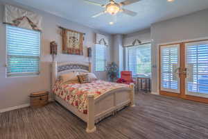 Bedroom with access to exterior, multiple windows, dark carpet, and a textured ceiling