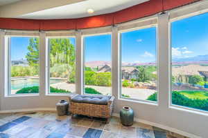 Sunroom / solarium with stone tile floors, a mountain view, and a residential view