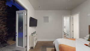 Bedroom featuring ensuite bathroom and dark tile patterned flooring