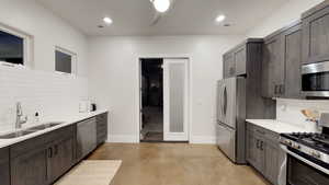 Kitchen with tasteful backsplash, stainless steel appliances, dark brown cabinetry, light stone countertops, and recessed lighting