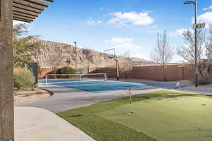 View of tennis court with a putting green, a mountain view, and basketball court