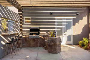 View of patio with exterior kitchen and a pergola