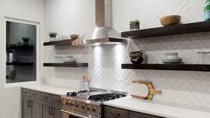 Kitchen with extractor fan, high end stainless steel range oven, dark brown cabinetry, open shelves, and backsplash