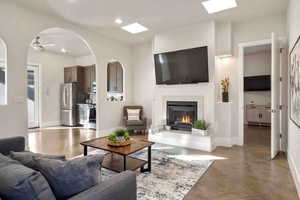 Living area featuring arched walkways, a premium fireplace, concrete flooring, recessed lighting, and a ceiling fan