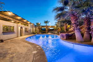 Pool at dusk featuring an outdoor pool, a pergola, and a patio area
