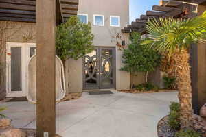Doorway to property with a pergola, french doors, and stucco siding