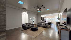 Living area with arched walkways and a ceiling fan