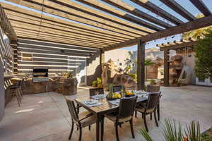 View of patio with exterior kitchen, outdoor dining space, and a pergola