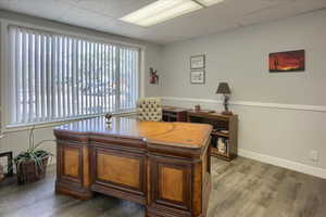 Office space featuring wainscoting, a drop ceiling, light wood-style flooring, and wood walls