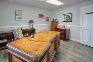 Office area featuring a drop ceiling, wood finished floors, and wainscoting
