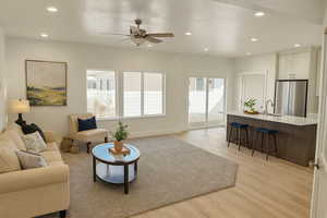Living room with a textured ceiling, light wood-style floors, ceiling fan, and recessed lighting