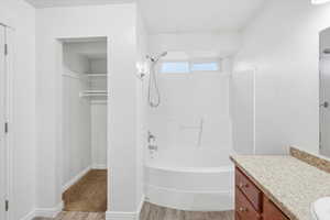 Bathroom featuring a walk in closet, vanity, bathing tub / shower combination, and light wood finished floors