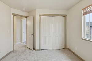 Unfurnished bedroom with light carpet and a closet