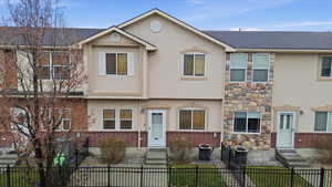 View of front of property with a fenced front yard, brick siding, and stucco siding