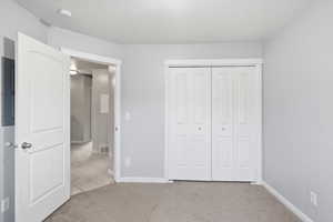 Unfurnished bedroom featuring light carpet, electric panel, and a closet