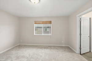 Unfurnished room with baseboards and light colored carpet
