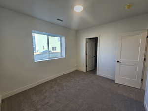 Unfurnished bedroom featuring baseboards and dark carpet