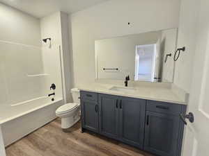 Bathroom featuring vanity, shower / tub combination, and dark wood finished floors