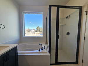 Full bath featuring a garden tub, vanity, and a stall shower