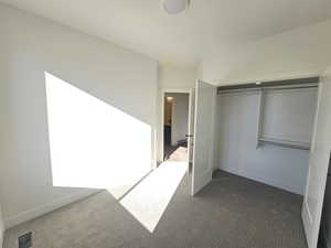 Unfurnished bedroom with dark carpet and a closet