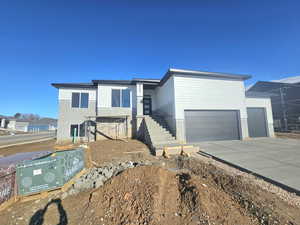 View of front of house featuring concrete driveway, an attached garage, and stairway