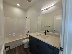 Full bath with bathtub / shower combination, vanity, dark wood finished floors, and recessed lighting