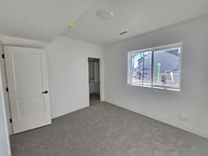 Unfurnished bedroom featuring a walk in closet and carpet flooring