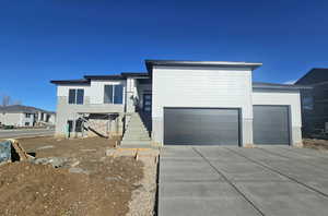 Contemporary home with concrete driveway, an attached garage, and stairway