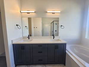 Bathroom featuring double vanity, a garden tub, and a stall shower