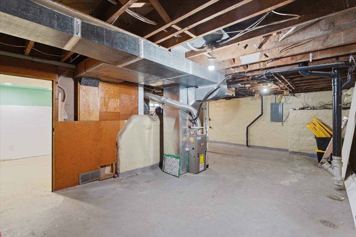 Unfinished basement with heating unit and electric panel