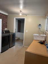 Washroom with separate washer and dryer, concrete flooring, and crown molding