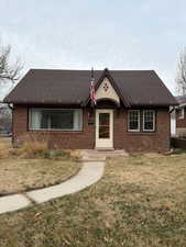 View of front of home featuring a front yard, brick siding, and a shingled roof