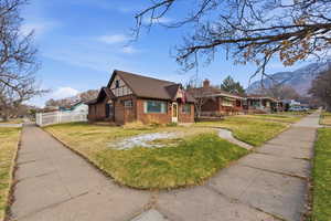 View of front of property with brick siding, a chimney, a mountain view, and a shingled roof