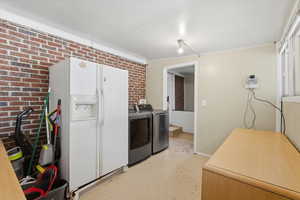 Washroom with brick wall, finished concrete floors, and washing machine and clothes dryer