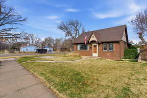 View of front facade featuring a front lawn, brick siding, and a shingled roof