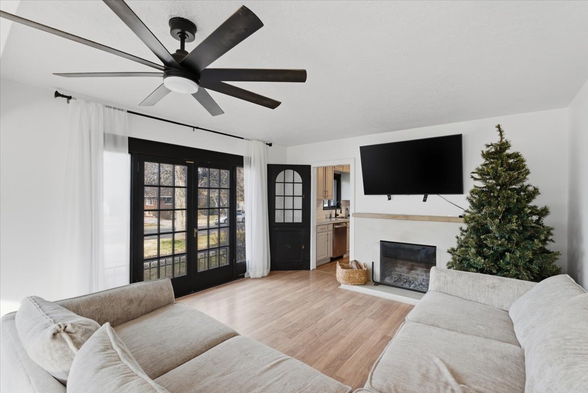Living area featuring a glass covered fireplace, light wood-style flooring, and ceiling fan
